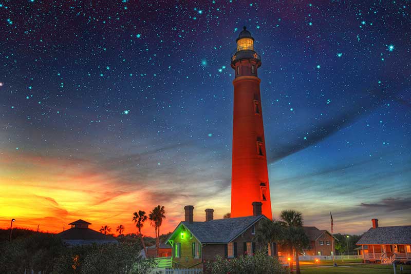 An orange sunset behind Ponce de Leon Inlet Lighthouse at Daytona Beach, Florida