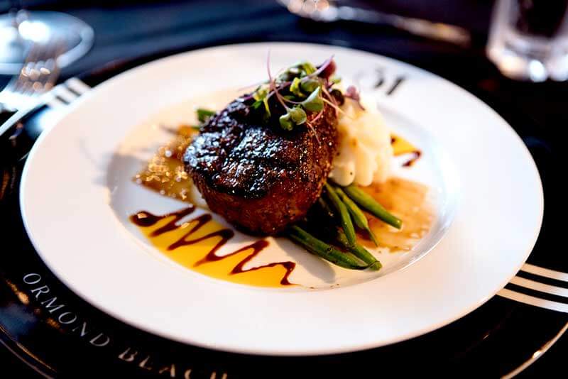 A round white plate with steak, green beans and mashed potatoes at 31 Supper Club in Daytona Beach, Florida