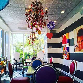 Restaurant decorated with wooden tables, jewel tone chairs and bright artwork at Candy Apple Cafe in Jacksonville, Florida