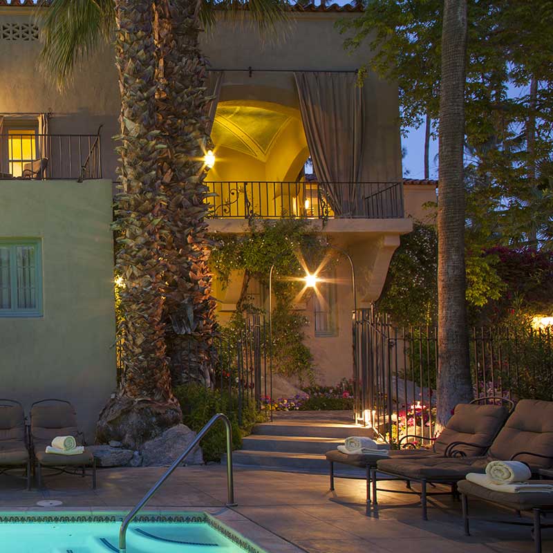 View of a lighted balcony by the pool at The Willows Historic Palm Springs Inn in California