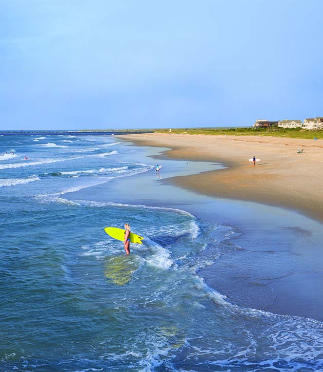 A Lifestyle Of Outdoors Downtime Fun In Carolina Beach Nc A Woman Stands In The Surf Holding Bright Yellow Surfboard Wrightsville Beach North