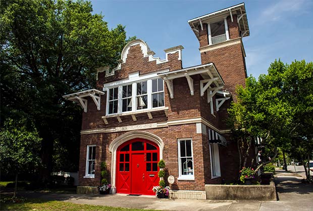 A brick building with a red door and decorative roofline houses Fifth & Castle Design Shop in Wilmington, North Carolina