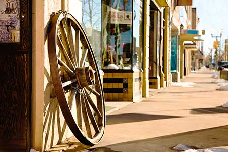 A wooden wagon wheel leans against a storefront in Laramie, Wyoming