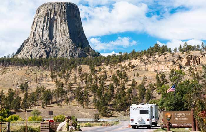 Devils Tower rises in the background as white RVs drive towards it in Gillette, Wyoming