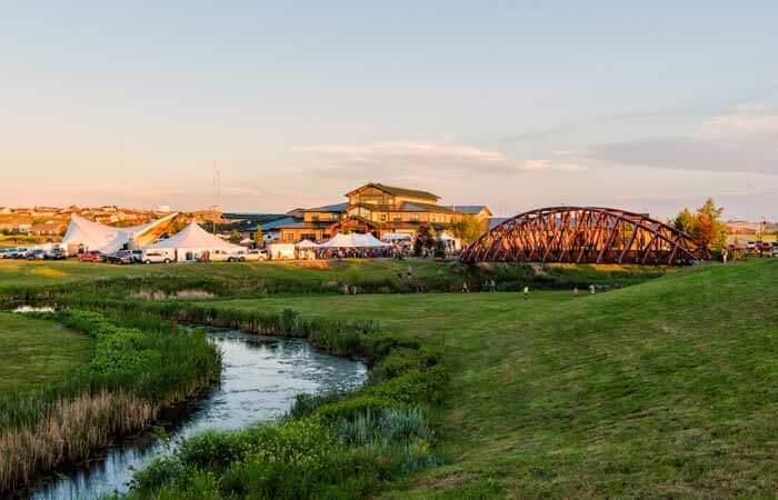 The Donkey Creek Music & Art Festival is set up in a grassy location with a river and bridge, in Gillette, Wyoming