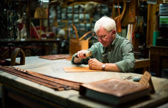 A seated man does leatherwork at King's Ropes & Saddlery in Sheridan, Wyoming