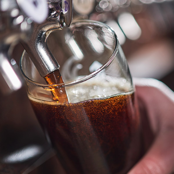 A close-up photograph of a beer being poured from a tap in Lincoln City, OR