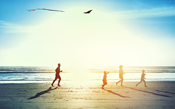 A family with two children fly kits on the beach at sunset in Lincoln City, OR