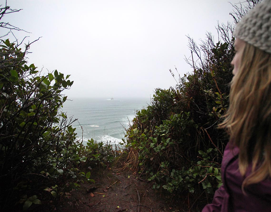 Woman looking out to Tillamook Rock Lighthouse in Seaside, Oregon