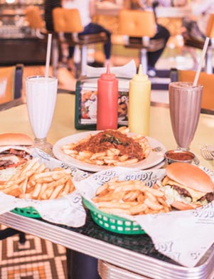 Baskets of hamburgers and french fries, tall milkshakes and ketchup and mustard on a table at Goody Goody in Tampa Bay, Florida