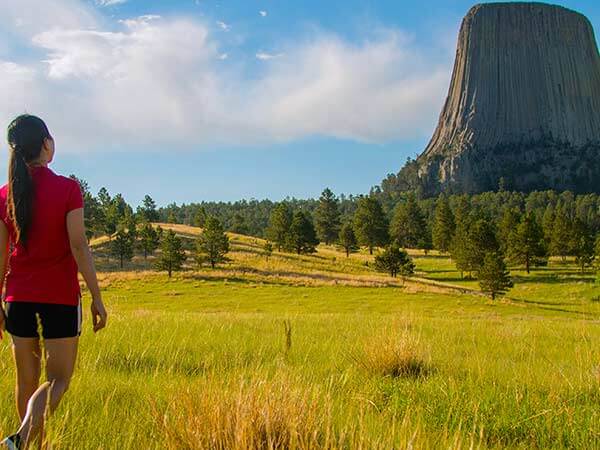 A woman in a red shirt looks at Devils Tower National Monument near Campbell County, Wyoming