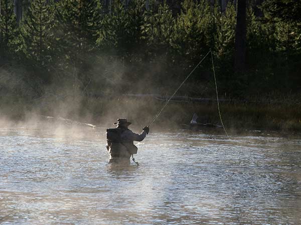A fisherman casts his line in a lake near the lodges of East Yellowstone in Wyoming