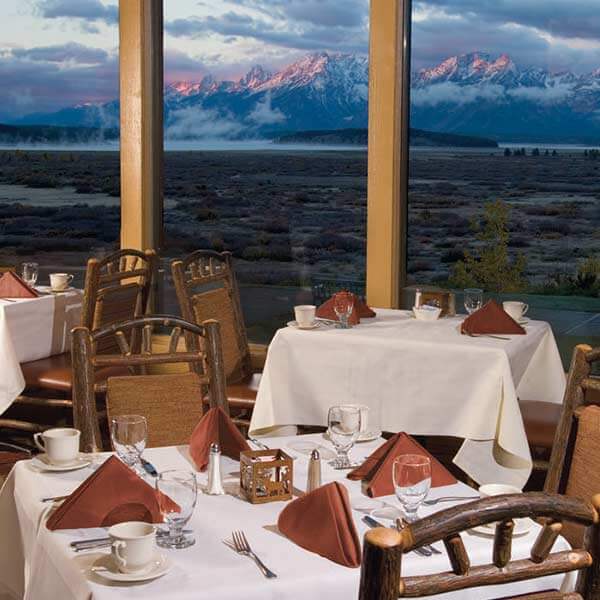 A view of the Teton Mountain Range behind dining tables in the Mural Room restaurant at Jackson Lake Lodge in Moran, WY