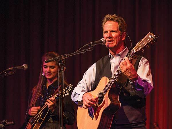 Dan Miller of Dan Miller’s Cowboy Music Revue plays guitar and sings into a microphone while performing in the Kuyper Dining Pavilion at the Buffalo Bill Center of the West in Cody, Wyoming