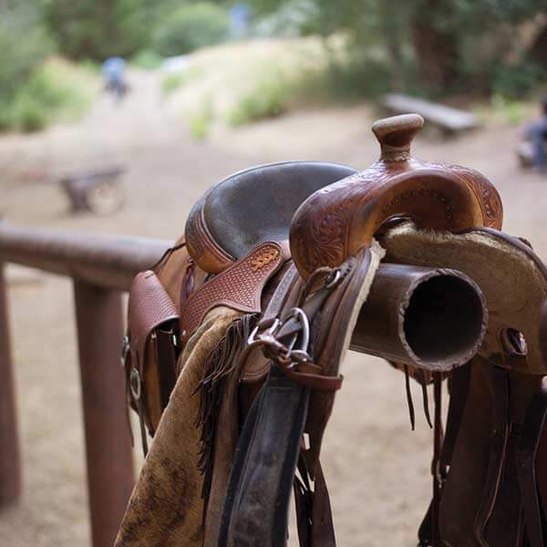 A brown leather saddle rests on a hollow metal railing in Park County, Wyoming