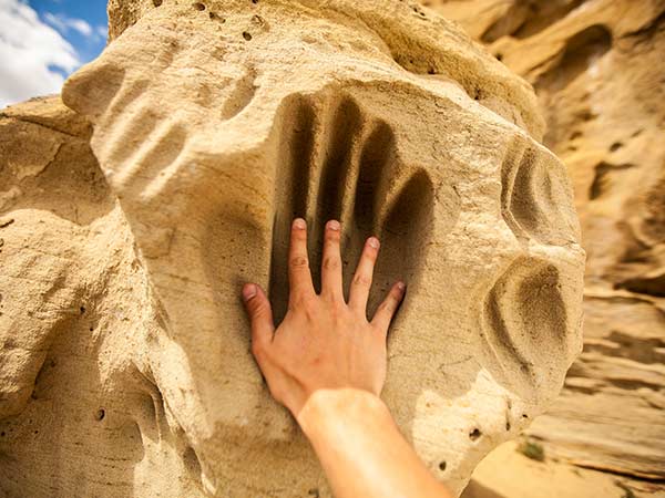 A hand touches the White Mountain Petroglyphs in Rock Springs, Wyoming