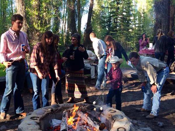 A family gathers around a campfire to roast marshmallows during a vacation at a Wyoming dude ranch