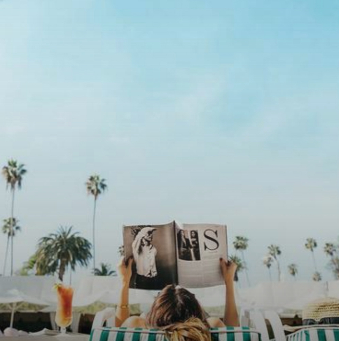 A woman reads by pool with a drink by her side at the Beverly Hills Hotel in Beverly Hills, CA. Instagram photo by @oddwie