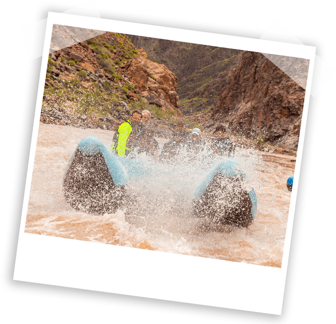 Un groupe de personnes monte sur un radeau avec les coureurs de la rivière Hualapai au Grand Canyon, tandis que de l'eau jaillit autour de leur radeau