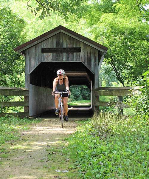 A cyclist rides across the Sugar River Trail covered bridge in Brodhead, Wisconsin.