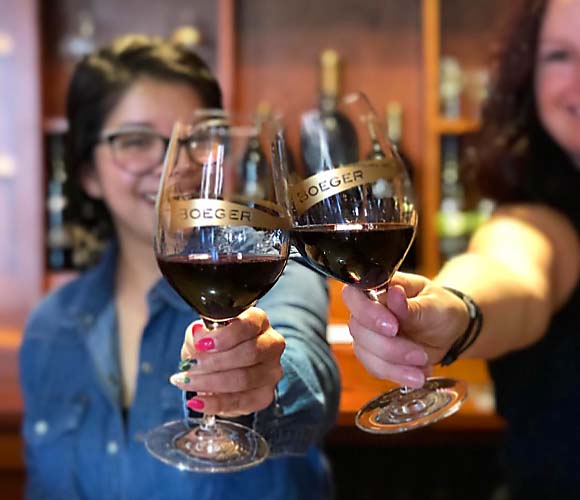 Two women toast wine glasses filled with red wine at Boeger Winery in Rancho Cordova, California.
