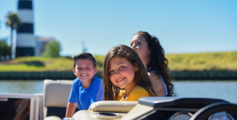 A boy and girl sit aboard a rented speedboat with their mother in Bay Area Houston