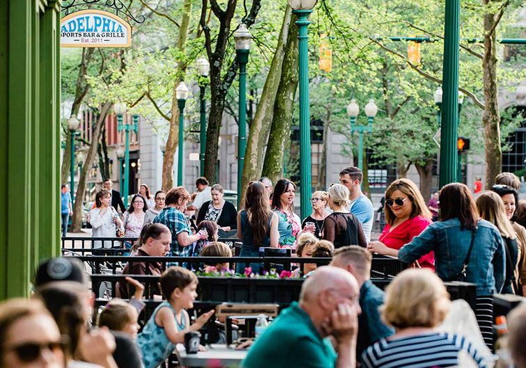 Dozens of people fill the outside patio and dining tables at Adelphia Sports Bar in Charleston, West Virginia. 