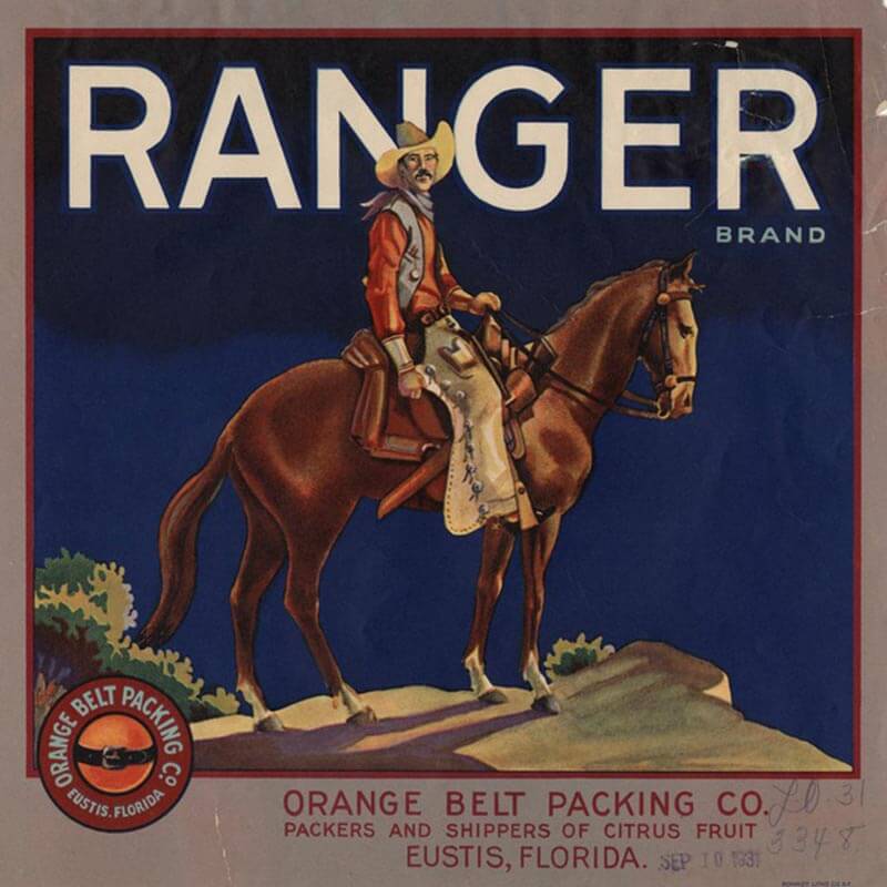 An illustrated Ranger brand citrus label has a blue background, white letters and a cowboy mounted on a brown horse.