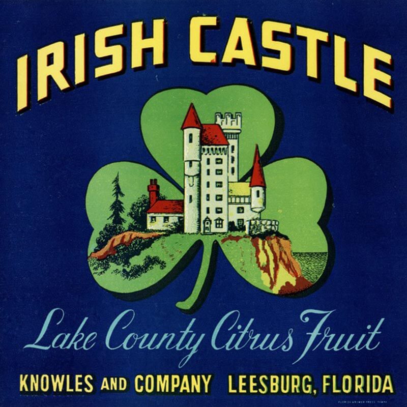 An illustrated Irish Castle brand citrus label is blue with yellow letters. A green shamrock has a tall castle shown in the center of it.