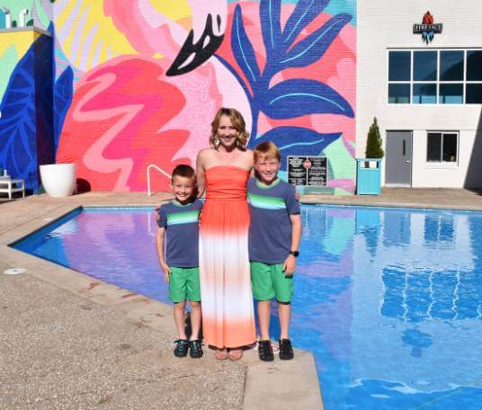 Woman and two little boys pose in front of an outdoor pool and mural at Oasis Hotel in Springfield, Missouri