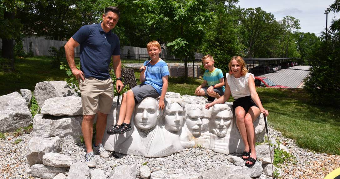 A father, a mother, and their two sons pose on top of a miniature Mount Rushmore at Getaway Golf in Springfield, Missouri