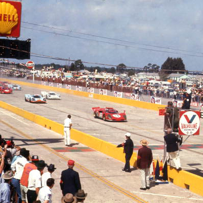 Visitors watch from the sideline as three sportscars zoom through a straightaway at the Sebring International Raceway in Sebring, Florida.