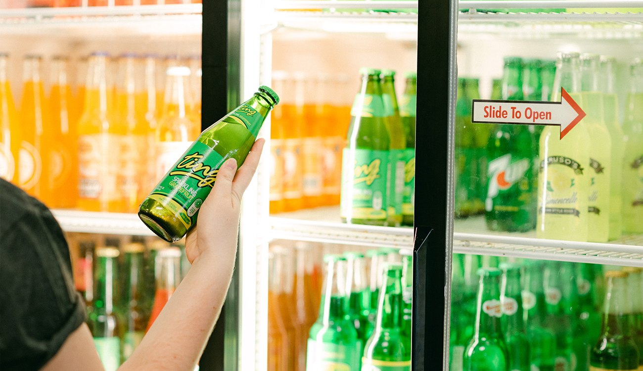 A green glass bottle of craft soda is removed from the refrigerated cooler at the Sebring Soda & Ice Cream Works in Sebring, Florida.