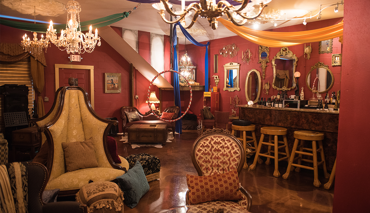 A sitting room at Mon Cirque Wine Bar is decorated in mismatched, antique chairs, pillows and chandeliers in Sebring, Florida.
