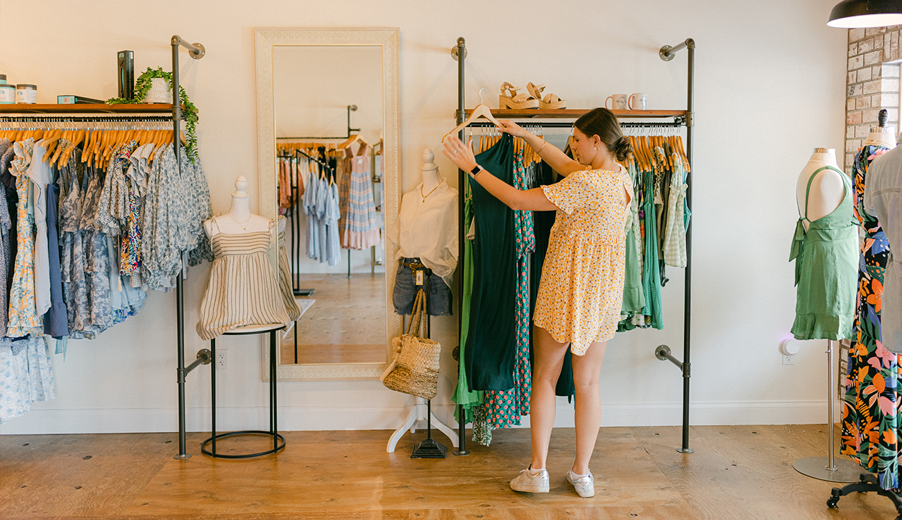 A female dressed in a yellow dress shops the racks at The Perry Co. Boutique in Lake Placid, Florida.