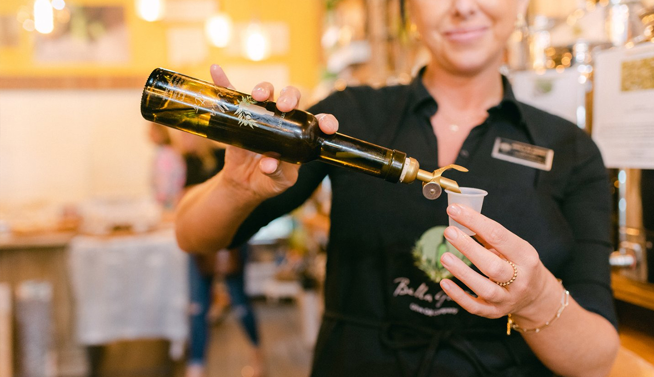A female worker in a black apron pours a sample of olive oil into a small plastic contatiner at Bella Gusto Olive Oil Co. in Lake Placid, Florida. 