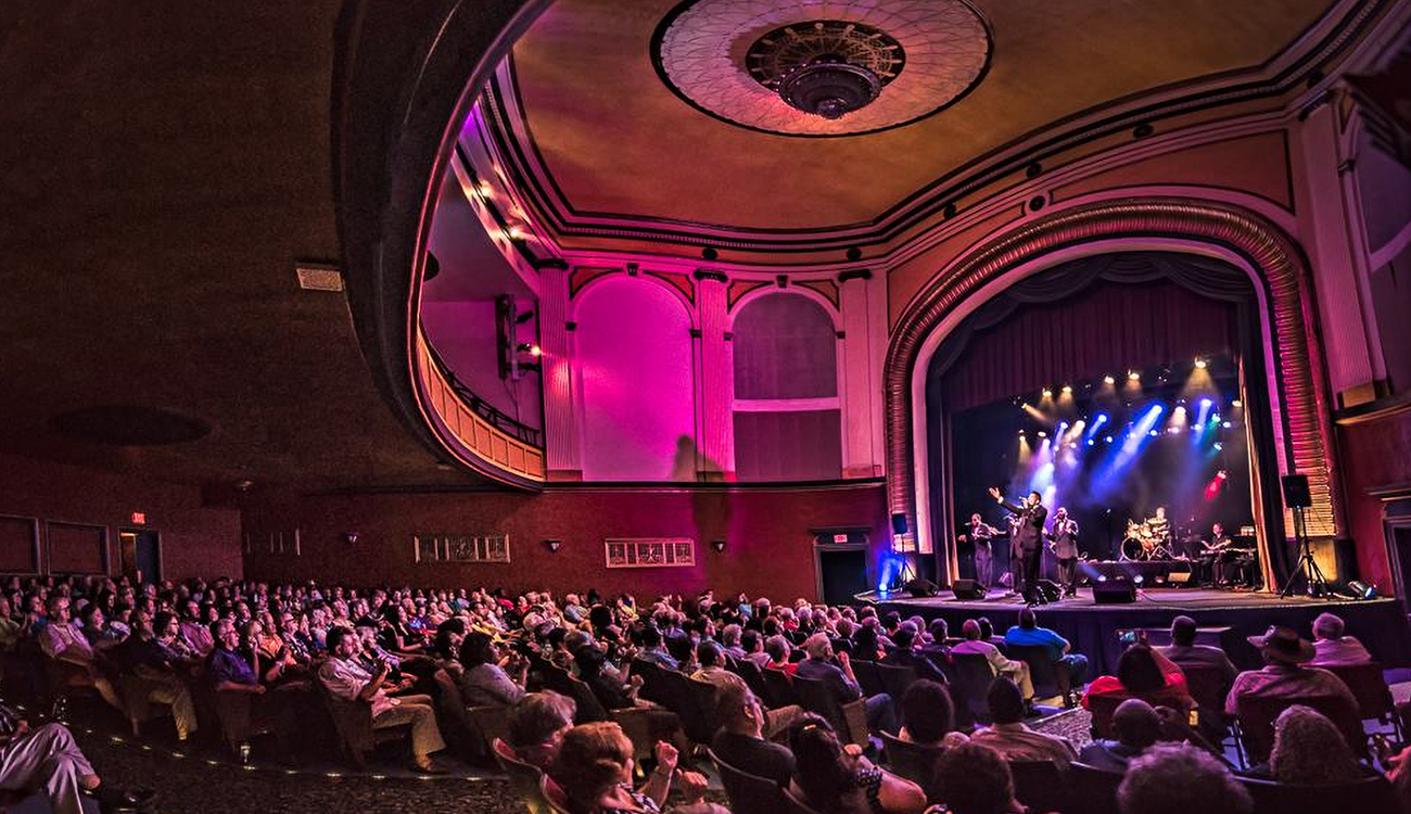 A six-person band performs to a full audience onstage at the Carolina Civic Center in Lumberton, North Carolina.